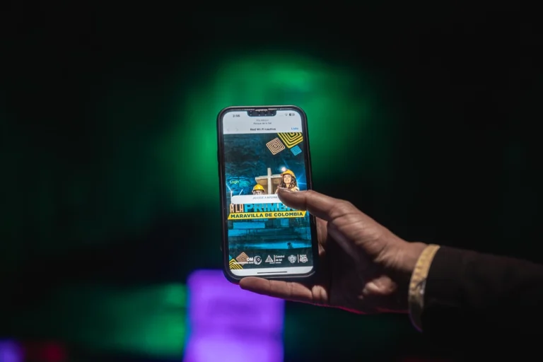 Mano sosteniendo un smartphone mostrando la página de inicio de la Catedral de Sal, usando el servicio Wi-Fi gratuito dentro de la maravilla de Colombia