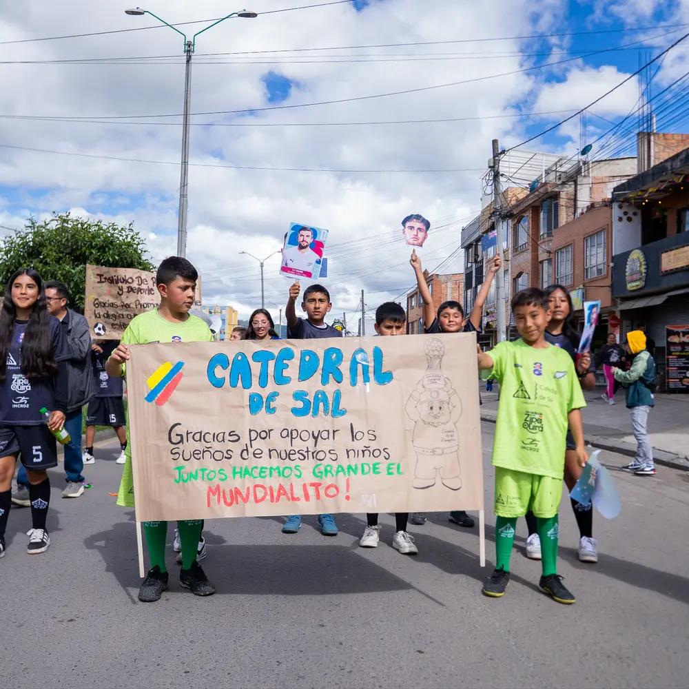 Niños y jóvenes marchan por las calles de Zipaquirá sosteniendo una pancarta artesanal que agradece a la Catedral de Sal por su apoyo al Mundialito.