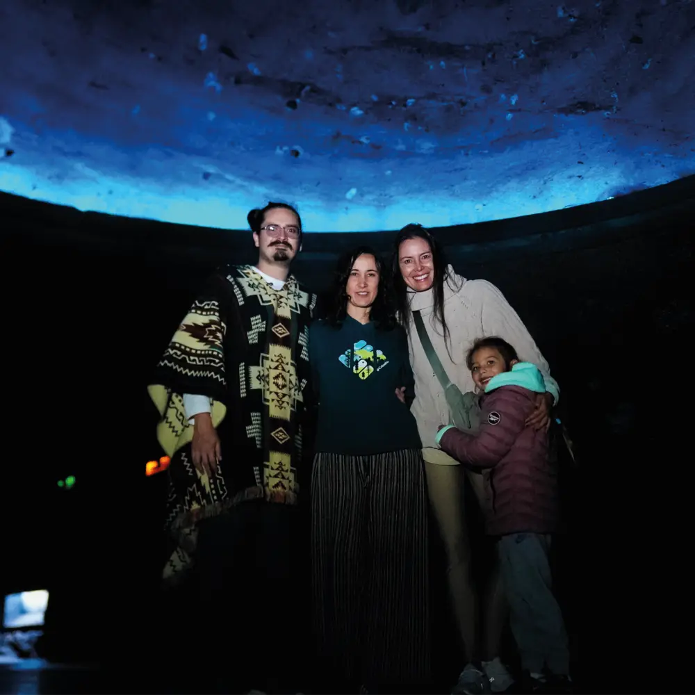 Un grupo de personas y una niña sonríen durante un recorrido familiar bajo la cúpula iluminada de azul en la Catedral de Sal de Zipaquirá.