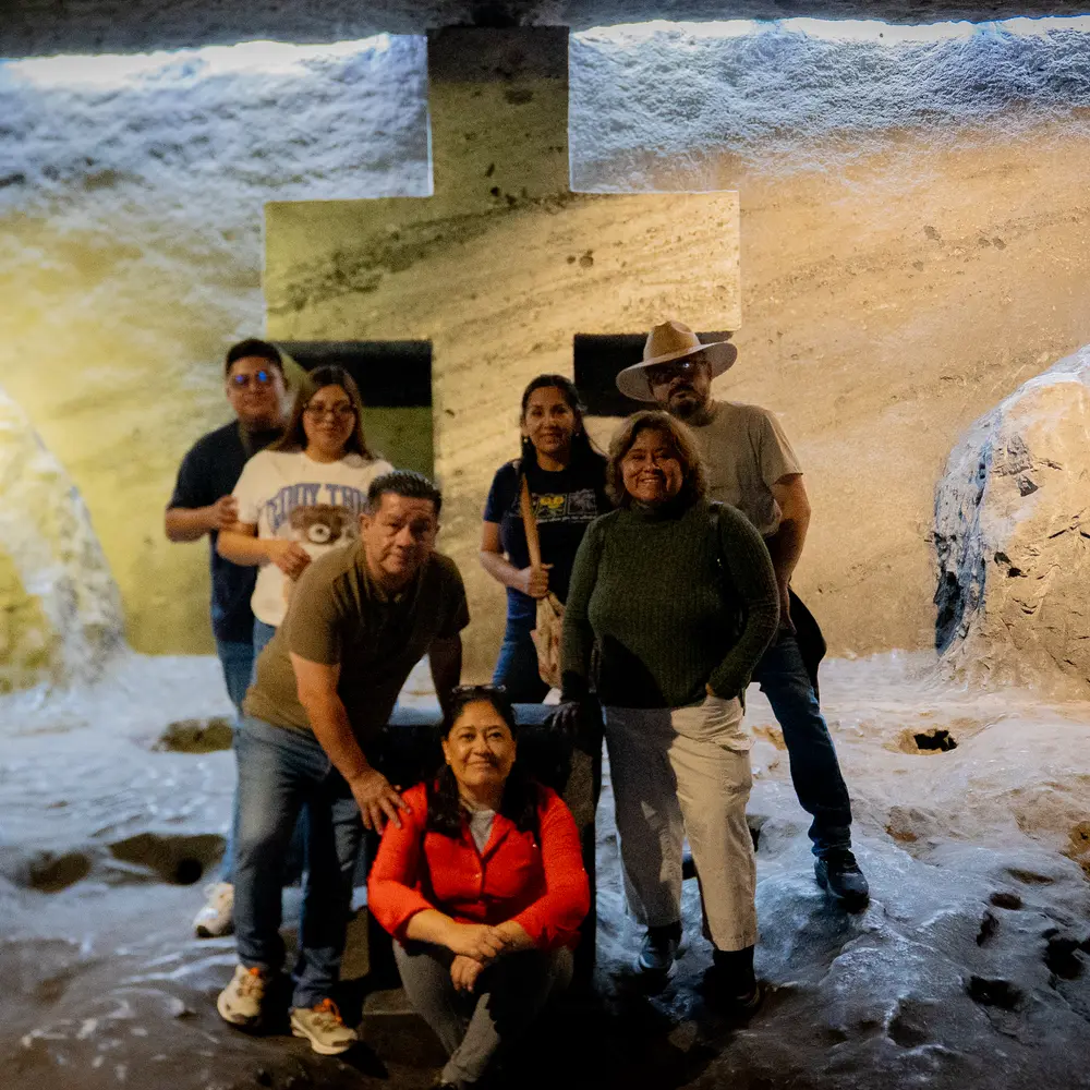 Grupo familiar posando juntos sonrientes frente a una cruz tallada en roca de sal dentro de la Catedral de Sal de Zipaquirá durante la temporada de Amor y Amistad