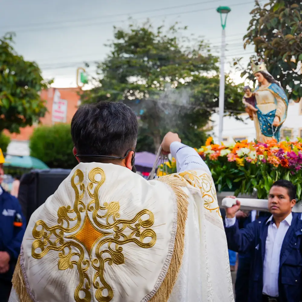 Un sacerdote con casulla bordada en oro incensa la imagen de la Virgen del Rosario de Guasá durante la procesión al aire libre en Zipaquirá.
